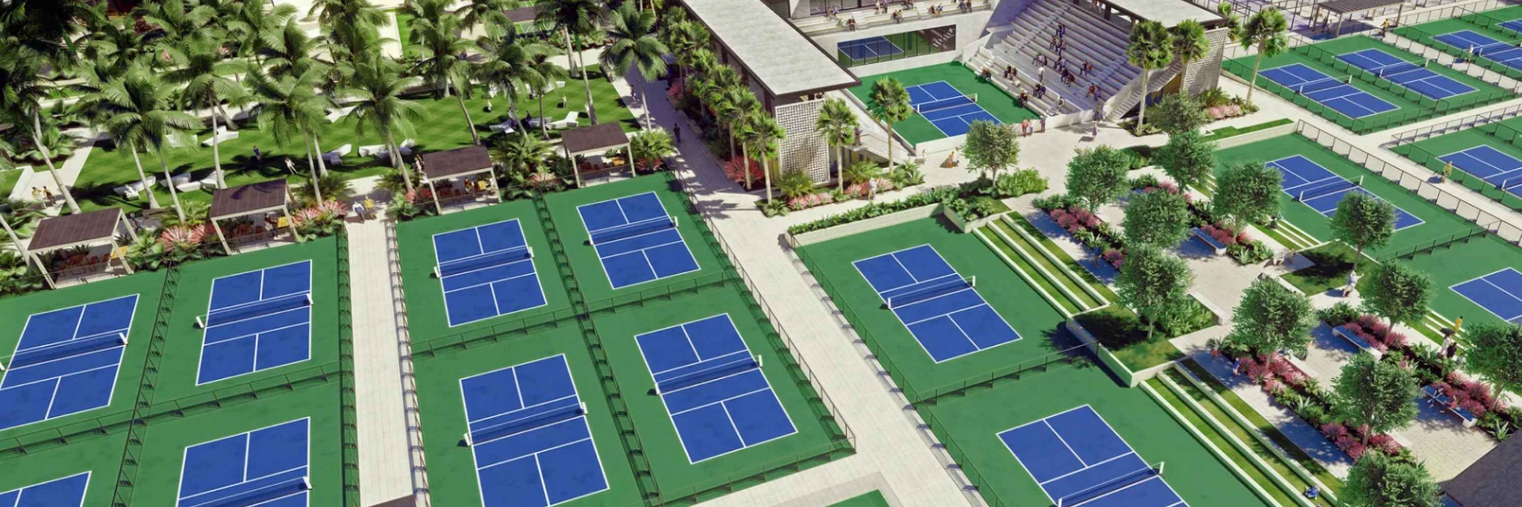 Aerial view of The Fort's expansive pickleball facility in Fort Lauderdale, featuring numerous blue-and-green courts, shaded cabanas, palm trees, and landscaped walking areas designed to foster social connection and leisure.